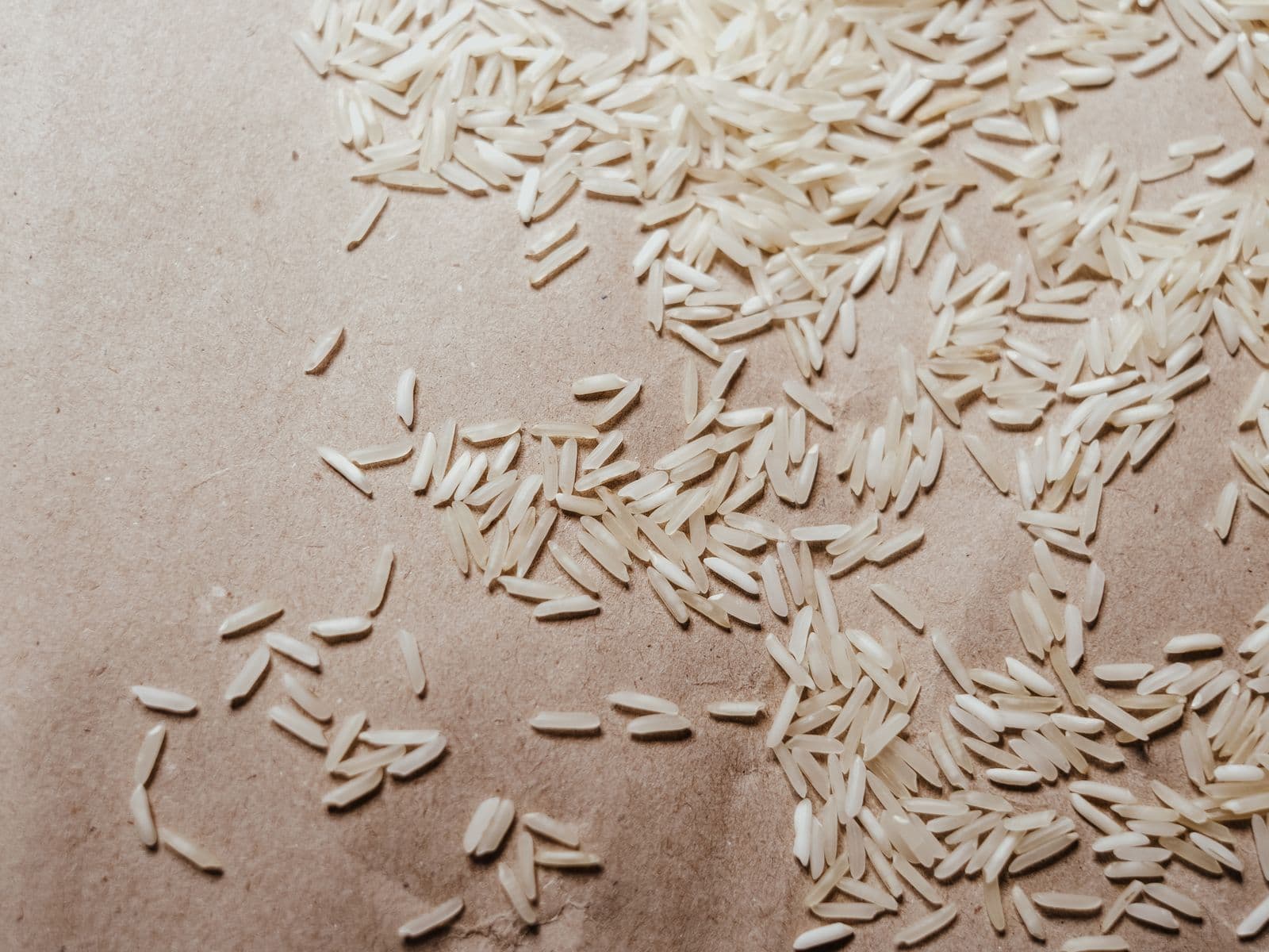 Extra-long white rice grains scattered across kraft paper.